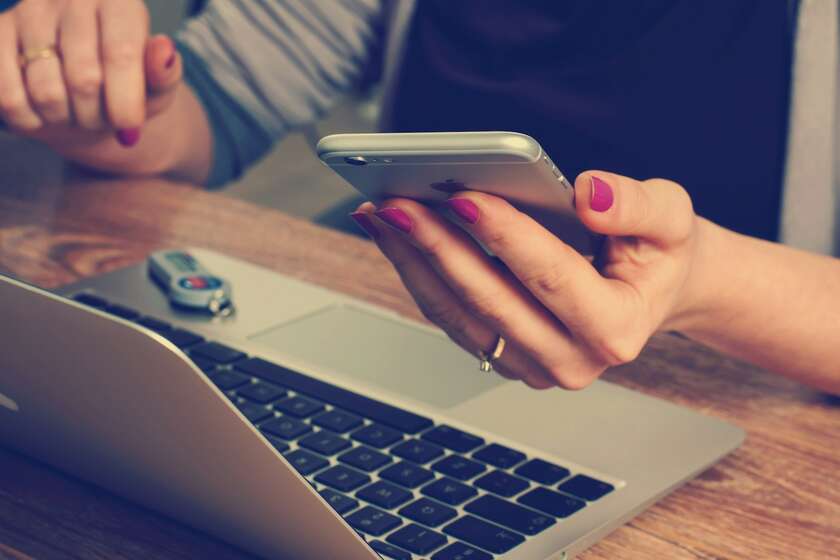 Une main tenant un smartphone sur un ordinateur portable