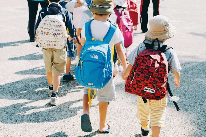 Des enfants qui marchent de dos avec un cartable