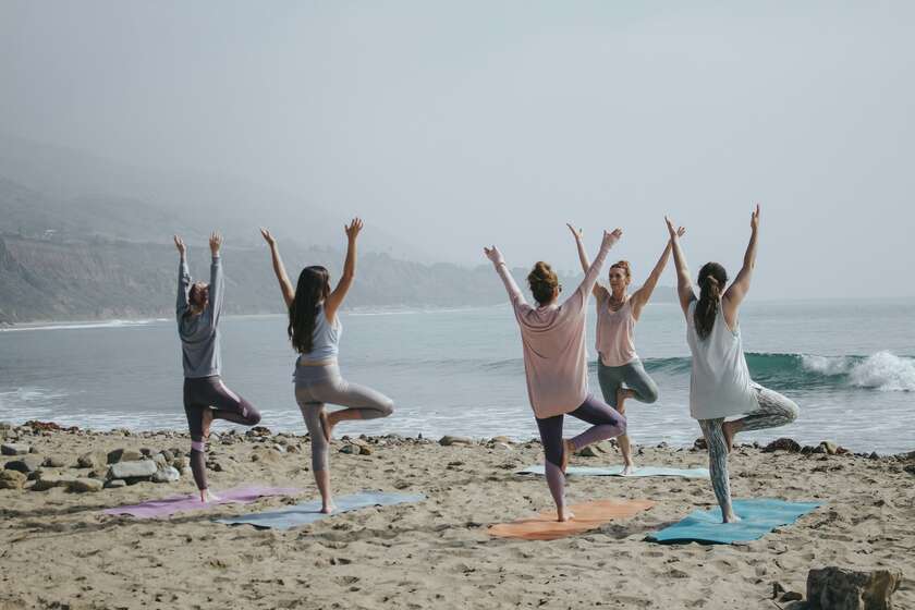 Des personnes qui font du yoga sur une plage de sable
