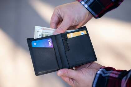 Des mains qui ouvre un portefeuille avec des cartes bancaires à l'intérieur