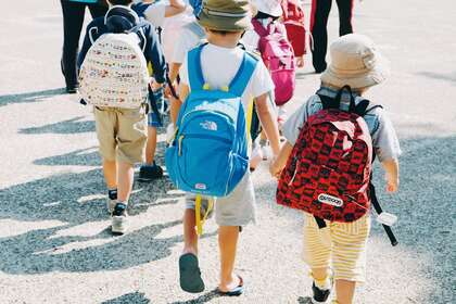 Des enfants qui marchent de dos avec un cartable