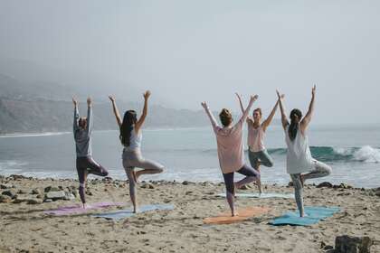 Des personnes qui font du yoga sur une plage de sable